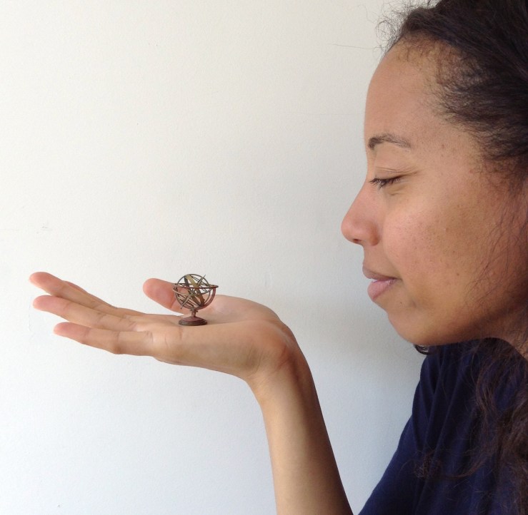 Woman holds 1:25 scale model of an astronomical model, an armillary sphere, on her outstretched palm